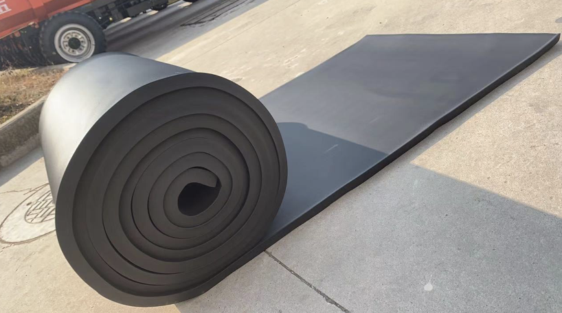 Rolled and flat black rubber insulation sheets beside a truck